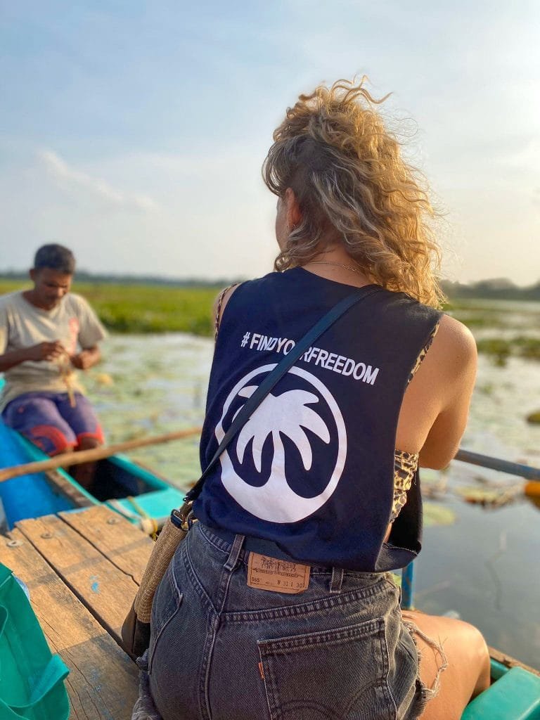 girl wearing Feel Free Travel vest while sitting on the side of a boat
