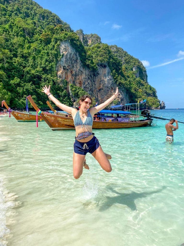 A girl jumping with excitement on a beach in Thailand