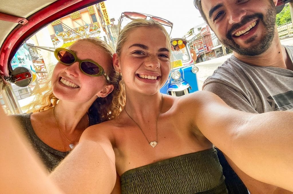 A group of people taking a selfie in a colorful tuk-tuk