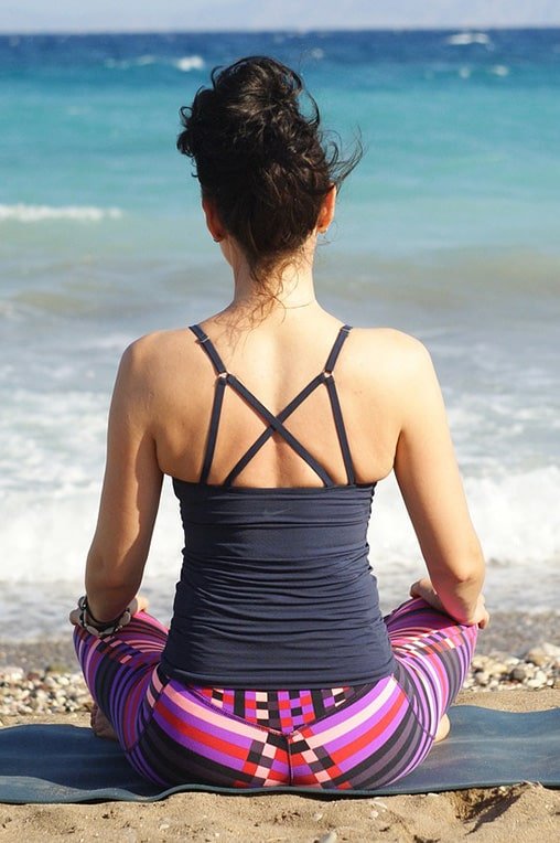 A picture of a woman doing yoga on the beach.