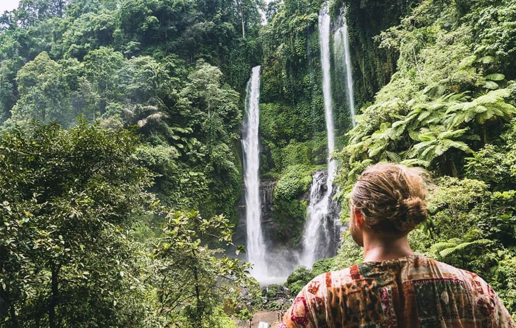 A picture of someone looling at a waterfall in Bali. 