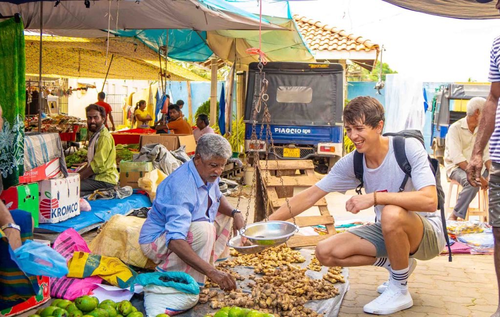 A lively outdoor market scene with a young traveler interacting with a local vendor amidst colorful stalls
