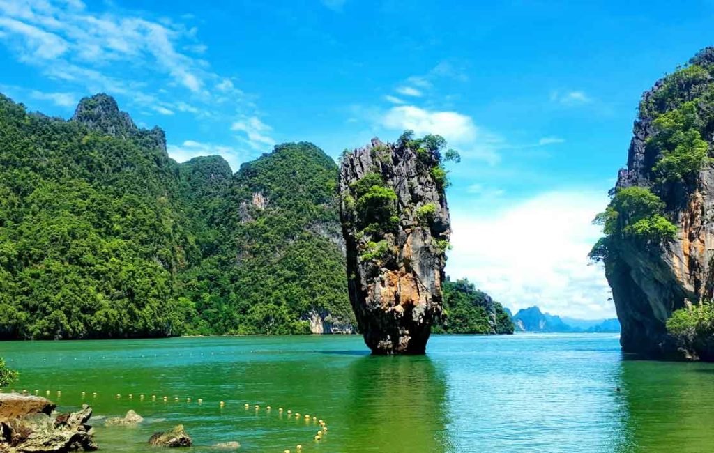 Iconic limestone rock formation rising from the emerald green waters of islands in Thailand.
