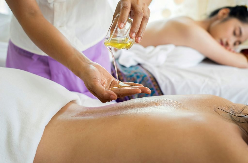 A relaxing spa treatment in progress with a masseuse pouring oil on a woman's back, symbolizing wellness and tranquility. Getting a massage is one of the best things to do in Sigiriya.